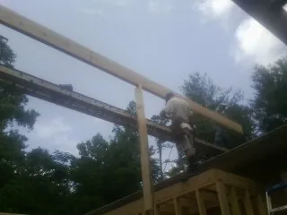 Carpenter setting a ridge beam over a new addition frame — Ice Dam Removal by Roofing Brothers in Miles City