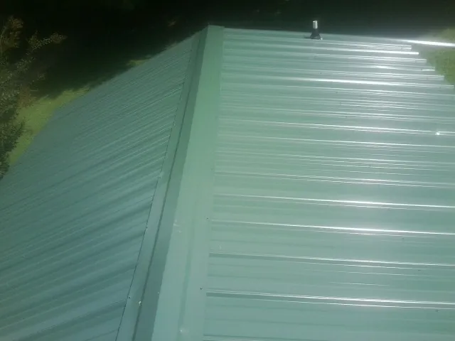New green metal panels meeting at the ridge of a roof — Flat Roof Repair work by our crew in Miles City