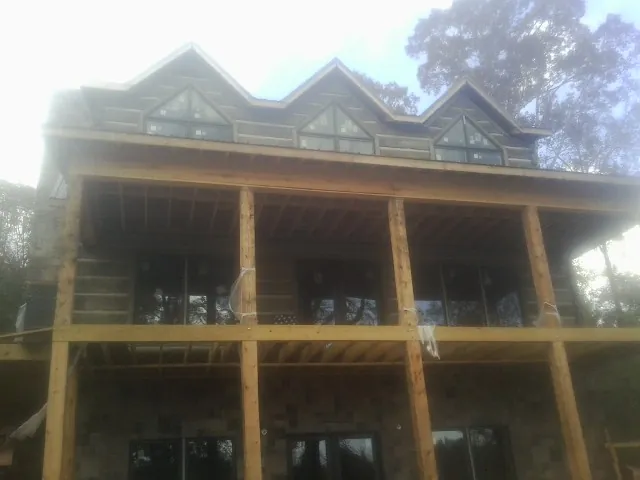 Dormers and porch framing on a large log home under construction — Roof Coating work by our crew in Miles City