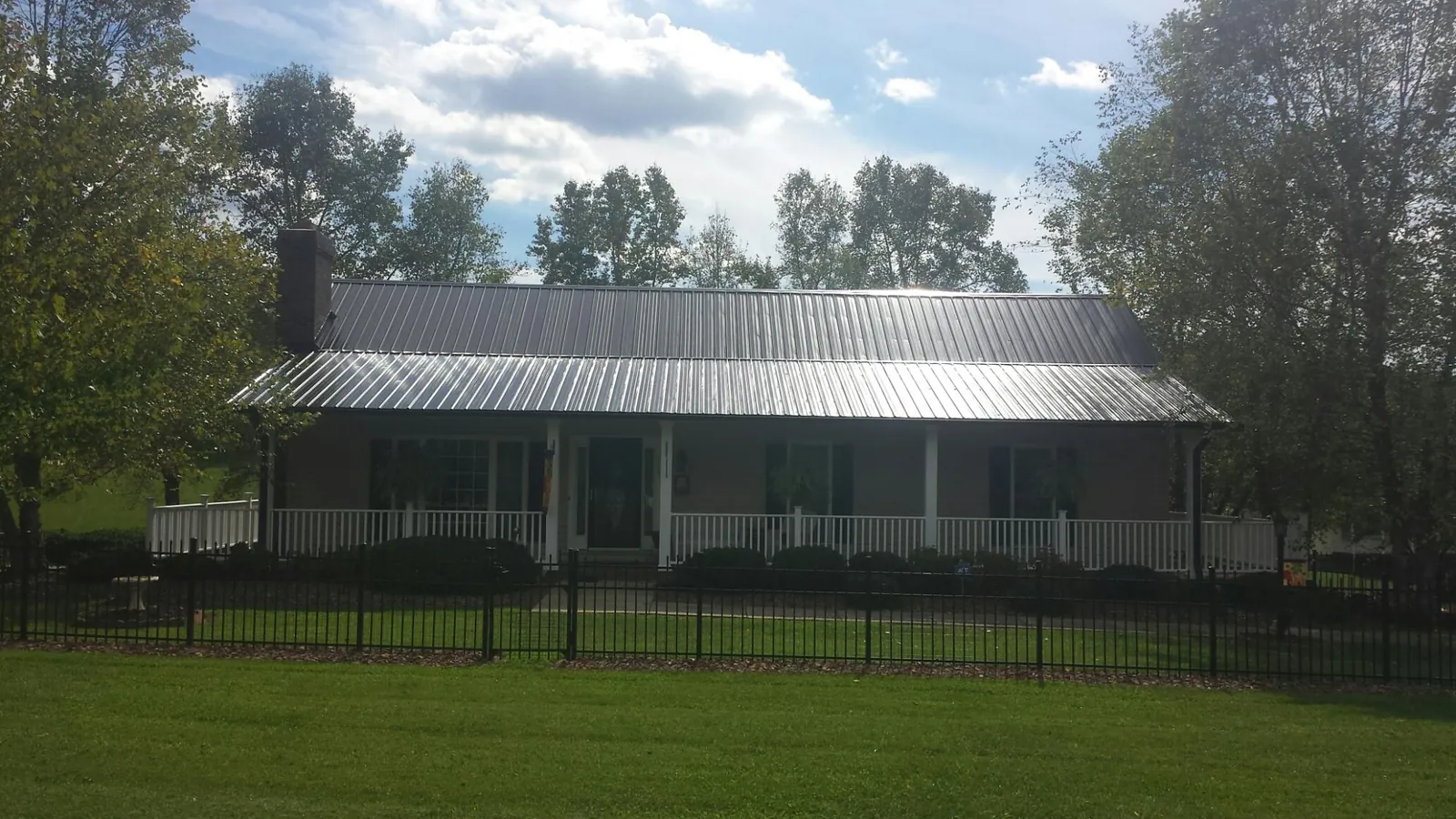 Gray metal roof on a brick ranch with a full width front porch — Gutter Guard Installation work by our crew in Miles City