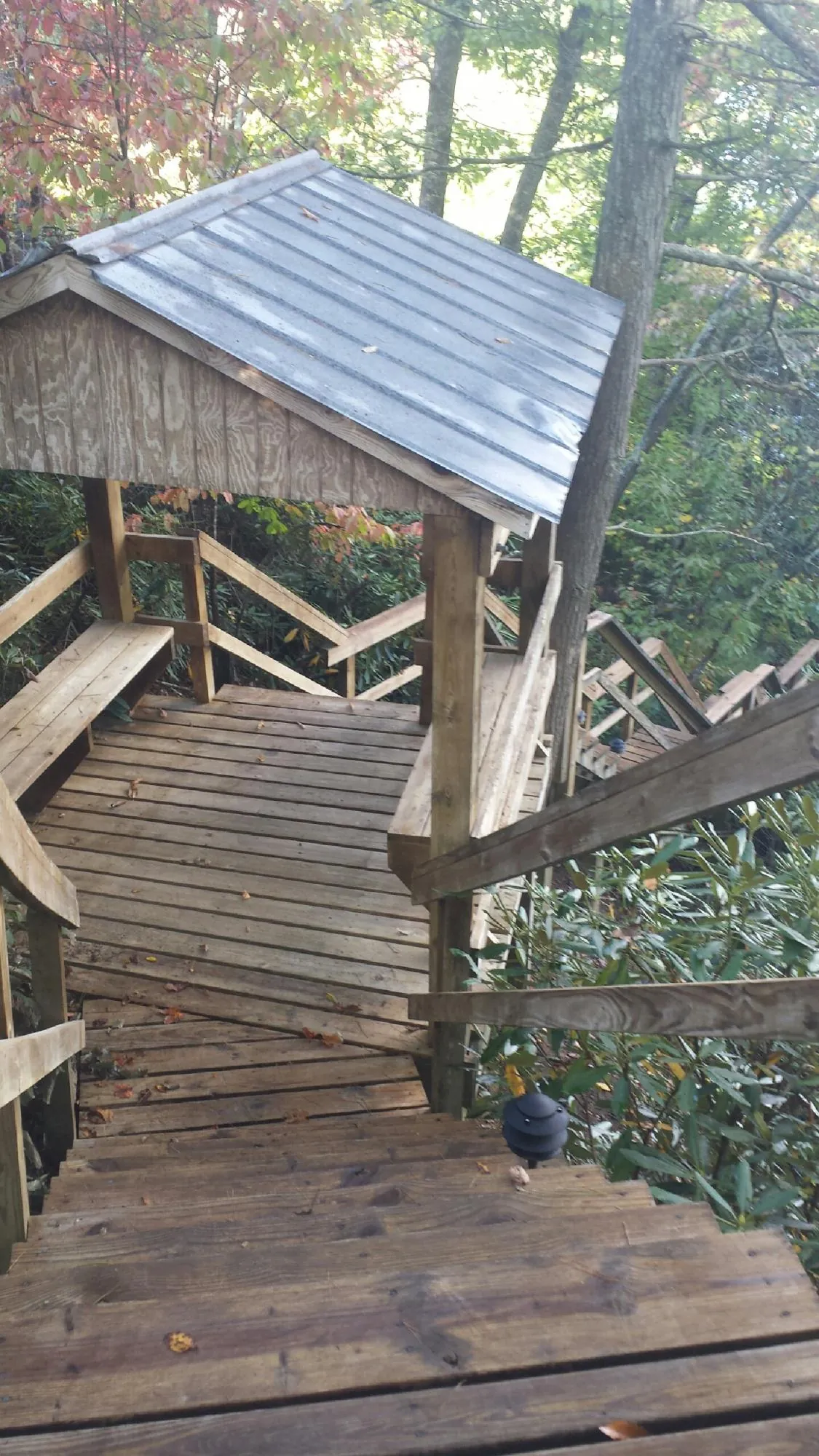 Metal roofed shelter over wooden steps on a wooded walkway — Skylight Repair & Installation work by our crew in Miles City