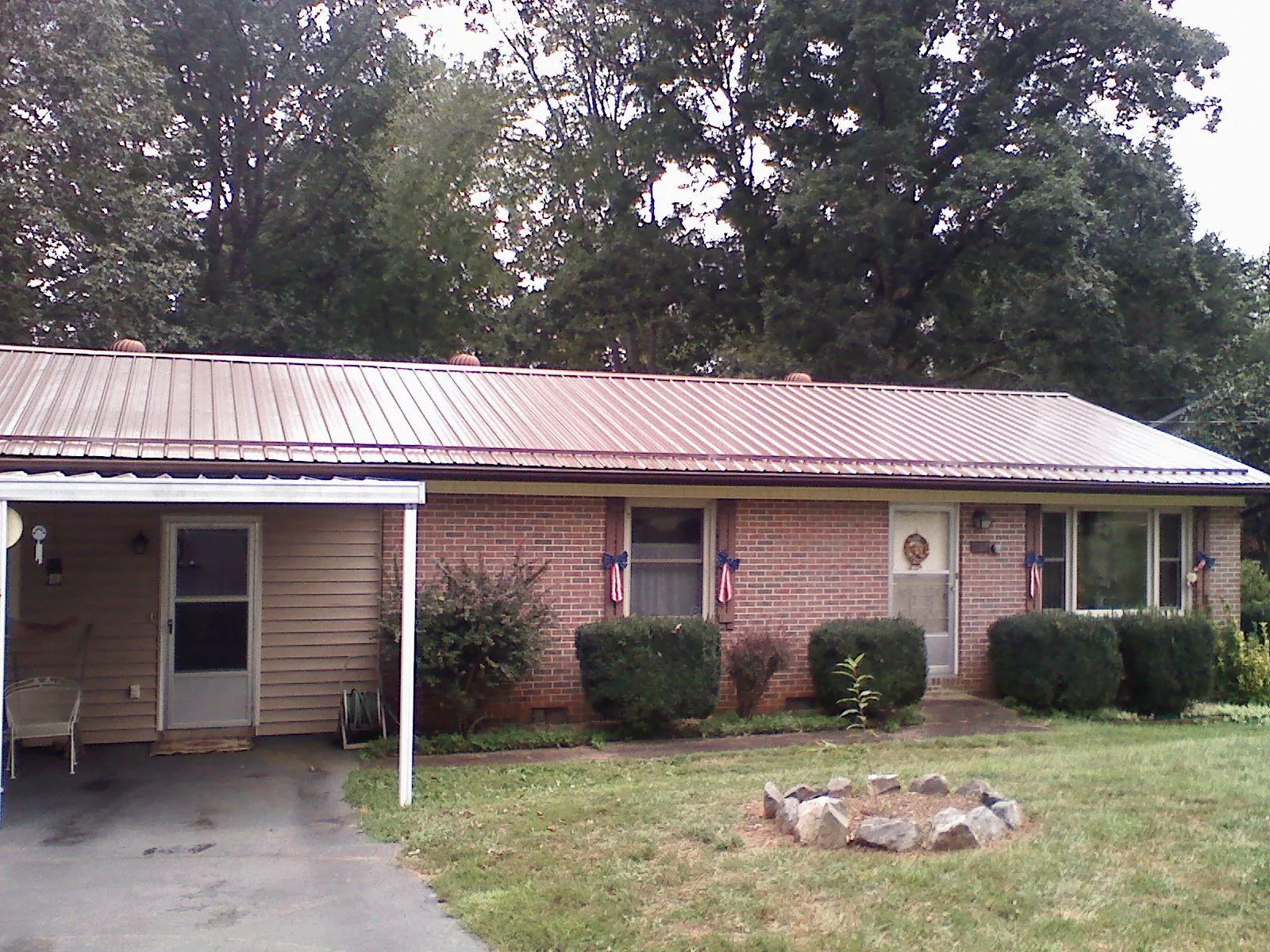 Bronze metal roof and carport on a brick ranch home — Roof Repair work by our crew in Miles City