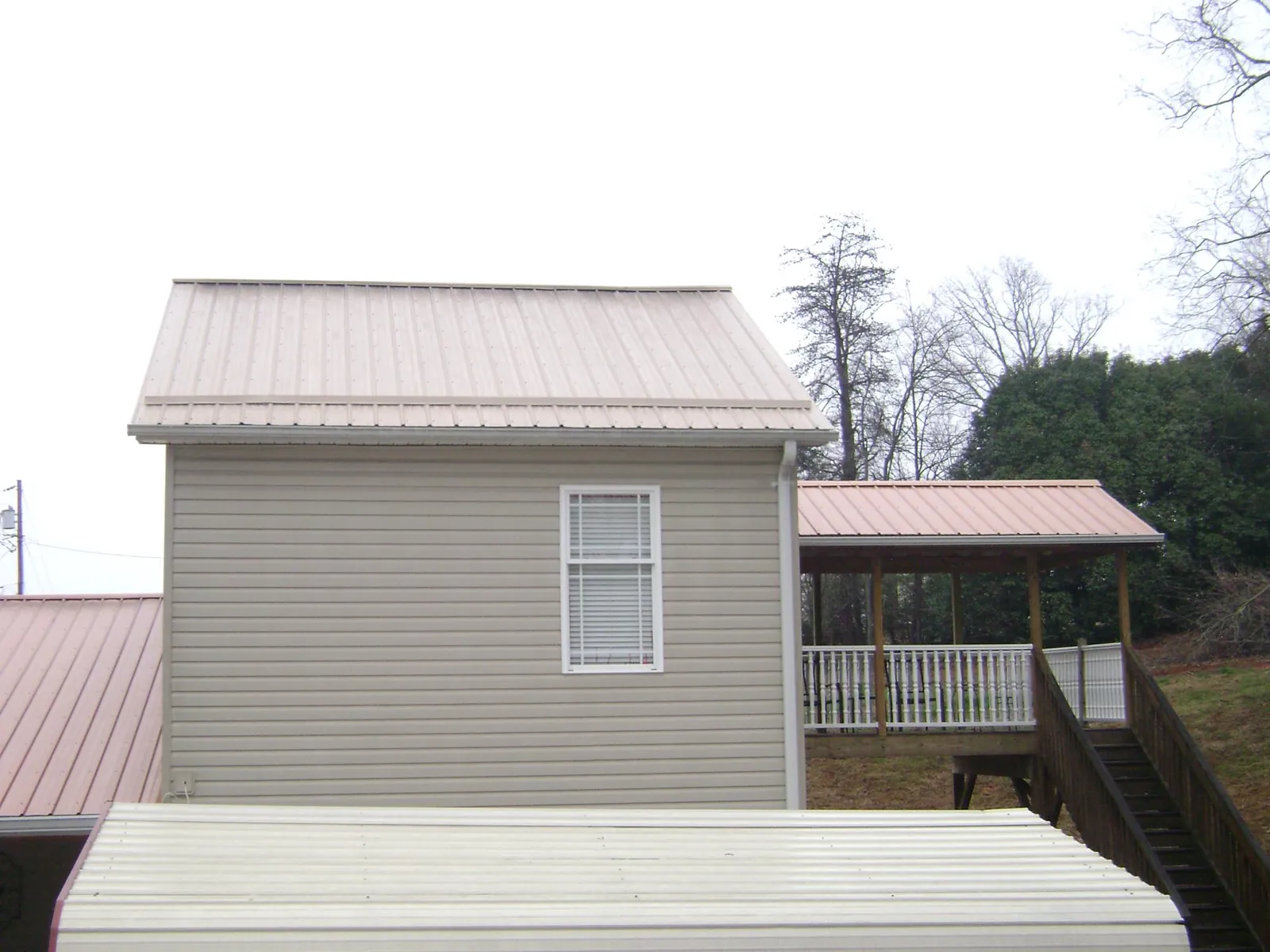 Tan metal roofs on a two story addition and attached porch, from a Roof Replacement job in Miles City