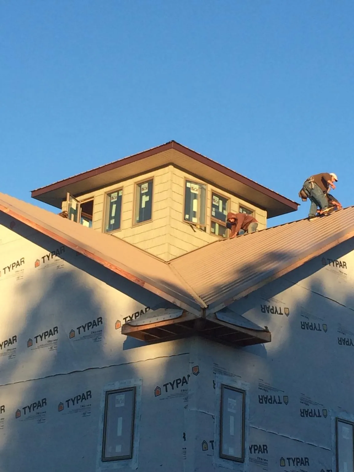 Roofers working around a rooftop cupola on a new metal roof at sunset — Roof Waterproofing in Miles City by Roofing Brothers